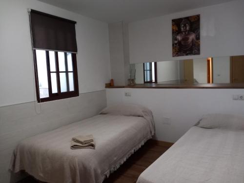 アンテケラにあるCorazón de Andalucíaのベッド2台、窓、鏡が備わる客室です。