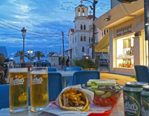 a table with a hot dog and two glasses of beer at Eden Suite Paralia in Paralia Katerinis