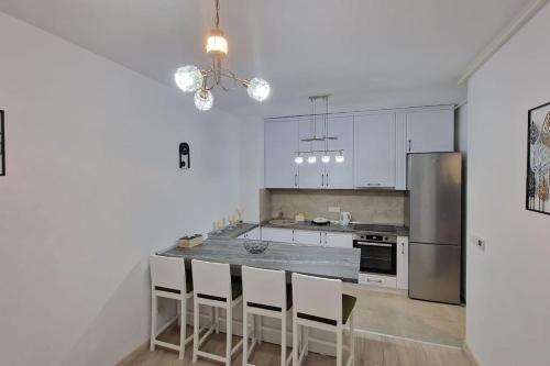 a kitchen with white cabinets and a counter with chairs at Apartament Adora Alex in Arad