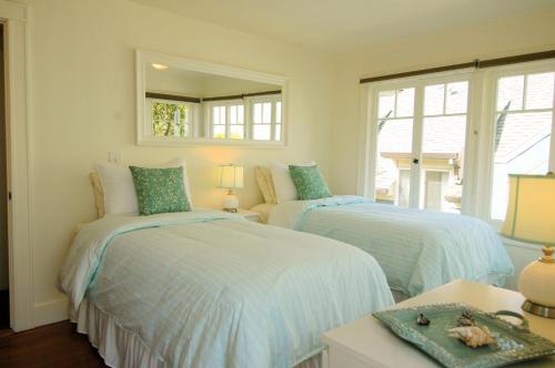 two beds in a room with a mirror at 3118 Yellow House Main home in Pacific Grove