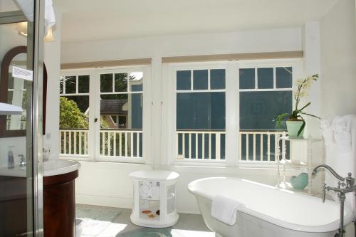 La salle de bains blanche est pourvue d'une baignoire et de fenêtres. dans l'établissement 3118 Yellow House Main home, à Pacific Grove