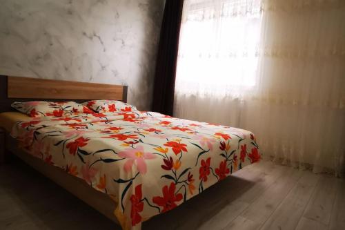 een slaapkamer met een bed met een bloemdekbed en een raam bij Two Bedroom Apartment in Roşu