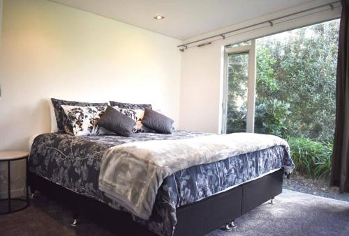 a bedroom with a bed and a large window at The Lakes - Kai Iwi Lakes Exclusive Retreat in Kaihu