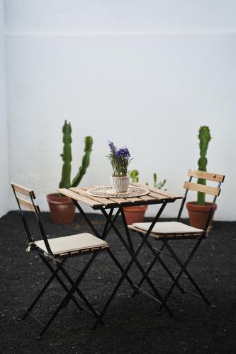 einen Holztisch, 2 Stühle und einen Tisch mit Pflanzen in der Unterkunft CASA MINGO in Teguise