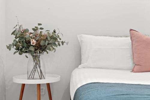 a vase of flowers on a table next to a bed at Paperbark in Evans Head
