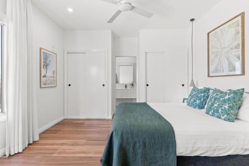 a white bedroom with a bed and a ceiling fan at Paperbark in Evans Head