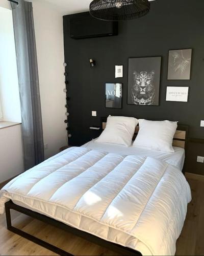 a large white bed in a bedroom with a black wall at Maison climatisée toute équipée in Montchanin