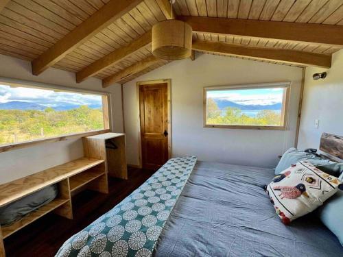 a bedroom with a bed and two large windows at Refugio Huerta Los Maquis in Puerto Guadal
