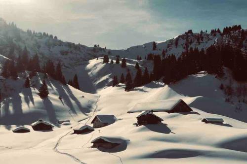 a snow covered mountain with a group of huts at Boutique Chalet Panoramic Views Hot Tub in Vers L'Eglise