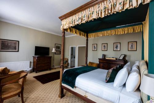 The George Inn في أوكهام: غرفة نوم مع سرير المظلة ومكتب