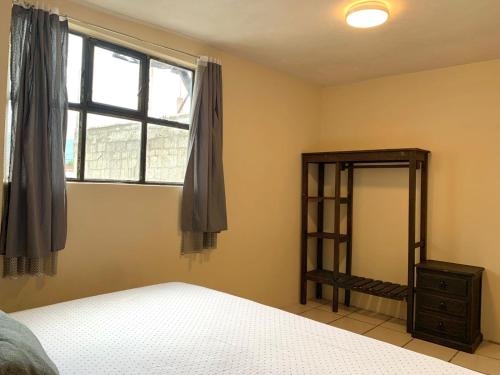Un dormitorio con una cama, una ventana y un espejo. en Habitaciones Sancris, en San Cristóbal de Las Casas