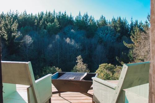 a grill on a patio with a view of a forest at Silvestre lodge in Buchupureo