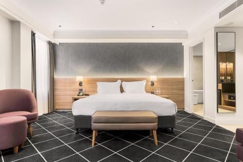 a bedroom with a large bed and two chairs at Holiday Inn Darling Harbour, an IHG Hotel in Sydney
