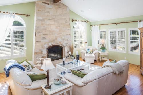 a living room with white furniture and a stone fireplace at 3485 Avalon by the Sea home in Monterey