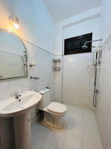 a white bathroom with a toilet and a sink at Muhsin Villa - Galle Fort in Galle