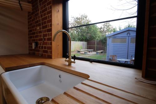 um lavatório de cozinha e uma janela com vista para um quintal em St Valentine - Fun away with loved ones em Manningtree