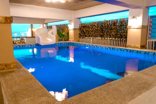 a swimming pool with a slide in a hotel room at Puffer Isle Resort in Dingalan