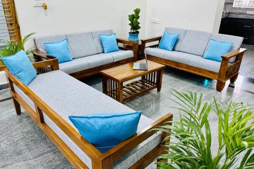 a living room with couches and blue pillows at TrueLife Homestays - Bhavya Manor - 2500 SFT Modern homes for family stay - Garden with Flowers - Tirumala Mountain View - Peaceful Location - Many restaurants nearby - Large hall, AC bedrooms, Modular Kitchen - Fast WiFi - Android TV - 250 Jio Channels in Tirupati