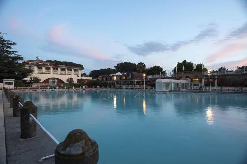 een groot zwembad met een gebouw op de achtergrond bij Le Magnolie Villa esclusiva vicino Roma e il lago in Nepi