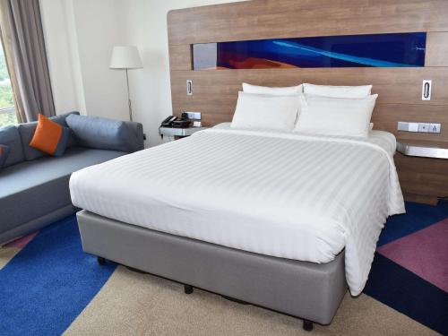 a bedroom with a large white bed and a couch at Novotel Taiping in Taiping