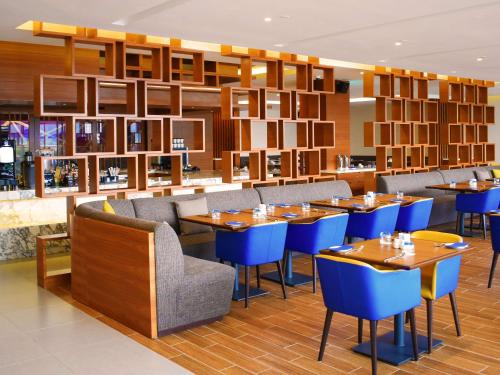 a restaurant with wooden tables and blue chairs at Novotel Taiping in Taiping