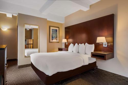 a hotel room with a large bed and a bathroom at Best Western Syracuse Downtown Hotel and Suites in Syracuse