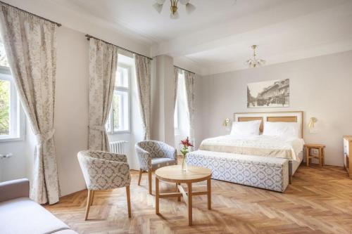 - une chambre avec un lit, une table et des chaises dans l'établissement Hotel At the Golden Scissors, à Prague