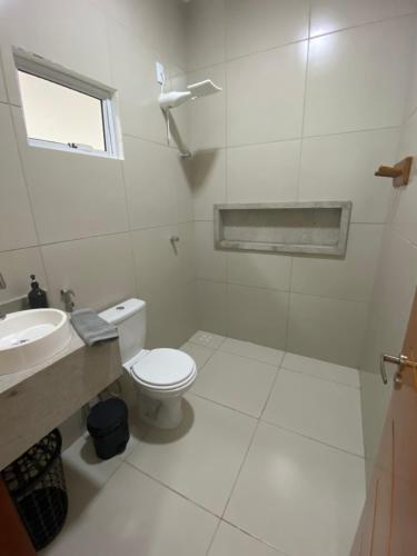 a white bathroom with a toilet and a sink at Casa Flecheiras 52 in Flecheiras