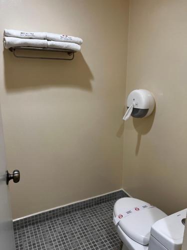 a bathroom with a toilet and a towel on the wall at Hotel Oliver Inn Toluca in Toluca