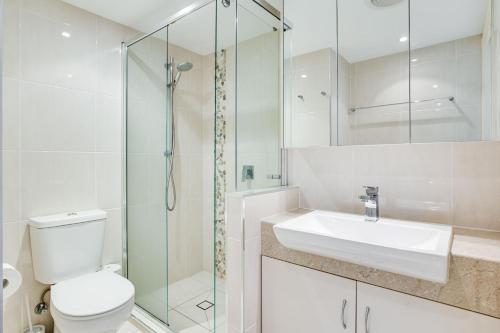 a bathroom with a toilet and a sink and a shower at Coral Sea Apartments in Maroochydore