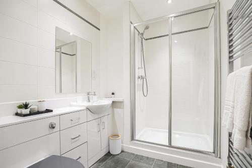 a white bathroom with a shower and a sink at Riverside Modern 2 Bedroom Flat in Glasgow