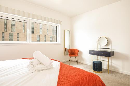 1 dormitorio con cama, espejo y silla en Riverside Modern 2 Bedroom Flat en Glasgow