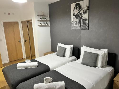 two beds in a hotel room with towels on them at Seven Suites - Beautiful 2-Bed Apartment with Parking in Watford Central in Watford
