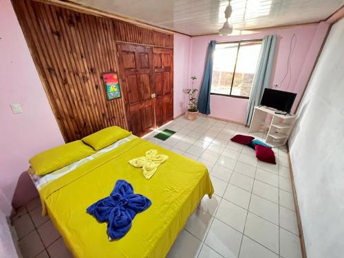 Un dormitorio con una cama amarilla con un arco azul. en Mochis en Quepos