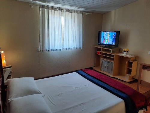 a hotel room with a bed and a television at Loftcharmoso2 in Pinhais