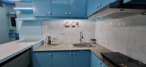 una cocina con armarios azules y fregadero en Mistow BriaScarlet Condo en Cagayán de Oro