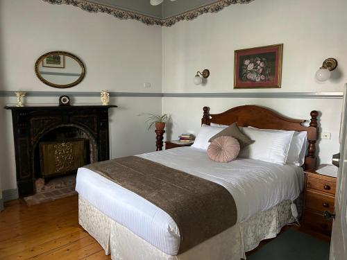 a bedroom with a large bed and a fireplace at Foundry Cottages in Rutherglen