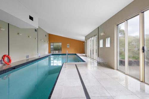a swimming pool in a building with a large window at Monument Chalet in Crakenback Resort in Crackenback