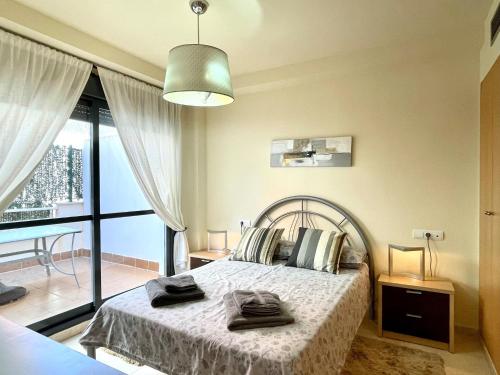 a bedroom with a bed and a large window at Apartment near beach with pools and hot tub in Los Amarguillos