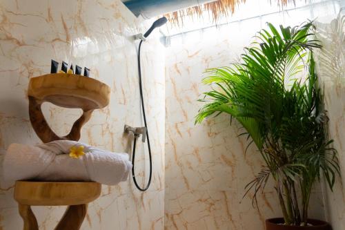baño con ducha, toalla y planta en Shray Villa. Legian, en Legian