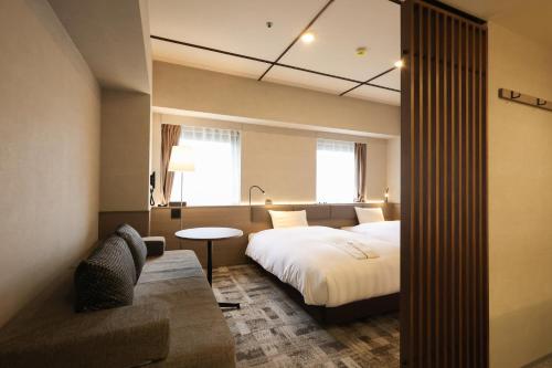神戸市にあるSK HOTEL 神戸駅前のベッドとソファ付きのホテルルーム