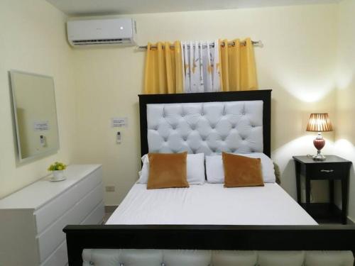 um quarto com uma grande cama branca e 2 almofadas em Hermoso y cómodo apartamento familiar en Ciudad Juan Bosch em Los Paredones