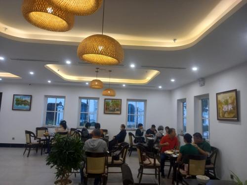 a group of people sitting at tables in a restaurant at INDOTEL HALONG HOTEL in Ha Long