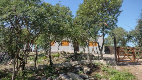 een hek met bomen en een huis op de achtergrond bij La Pasionaria Casa de Campo in Agua de Oro