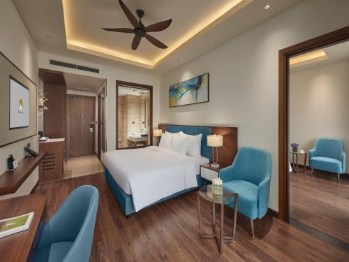 a hotel room with a bed and two blue chairs at The Watson Premium HaLong Hotel in Ha Long