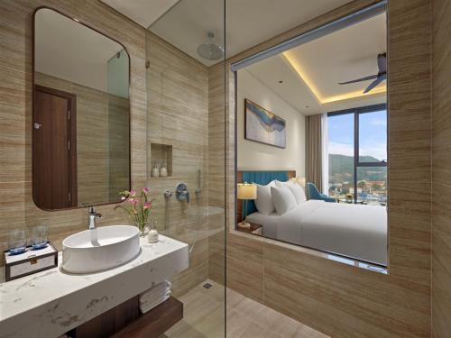 a bathroom with a sink and a bed and a mirror at The Watson Premium HaLong Hotel in Ha Long