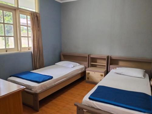 two beds in a small room with two windows at Villa Landis Resort in Pacet