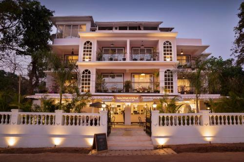a large white building with a lit up facade at Mademoiselle Boutique Resort and Cafe in Vagator