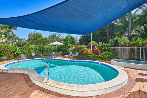 - une piscine avec un parasol bleu dans l'établissement Private Argosy Apartment, à Clifton Beach