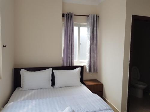 um quarto com uma cama com lençóis brancos e uma janela em Hong Vinh Hotel em Ho Chi Minh